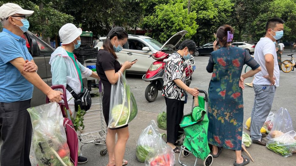 Vecinos hacen cola para comprar verdura antes de que empiece el confinamiento en Chengdu.