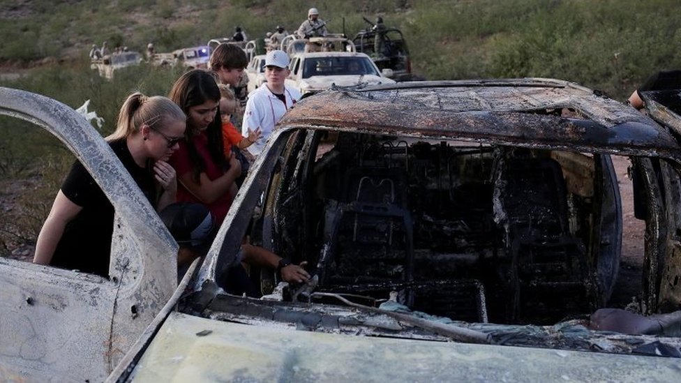 Родственники убитых членов мексикано-американских семей, принадлежащих к мормонским общинам, наблюдают сгоревшие обломки автомобиля, на котором погибли некоторые из их родственников