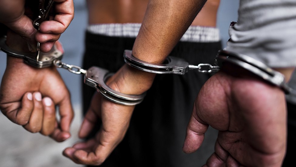 Two men are handcuffed in a prison in El Salvador.
