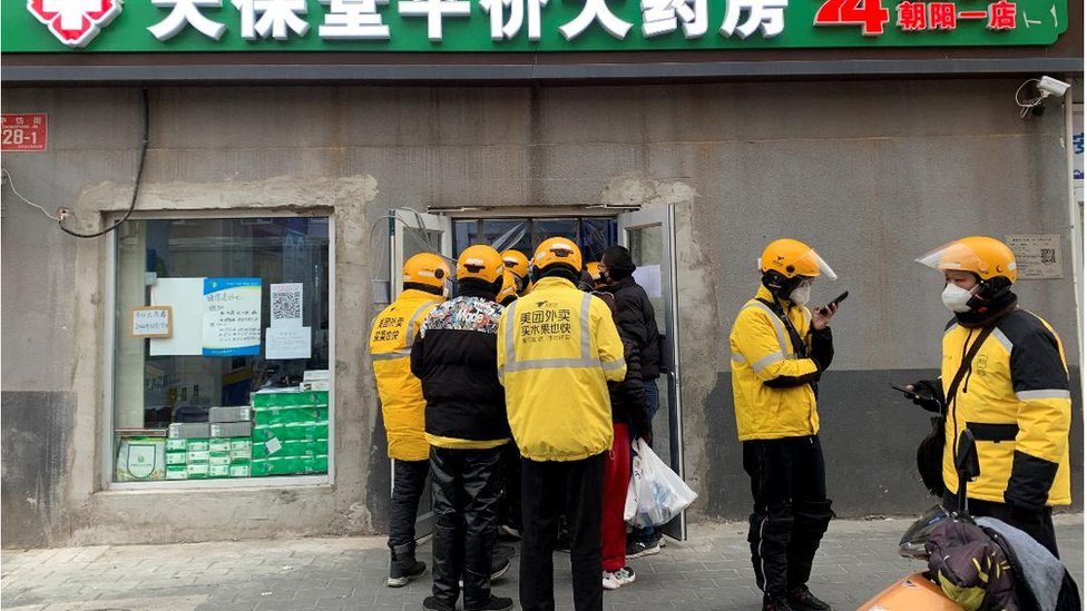 Delivery workers wait outside a pharmacy to pick up orders as coronavirus disease (COVID-19) outbreaks continue in Beijing, December 20, 2022
