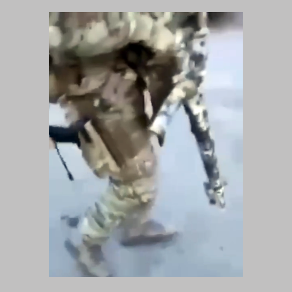 Still from the video showing a soldier carrying a camouflaged assault weapon