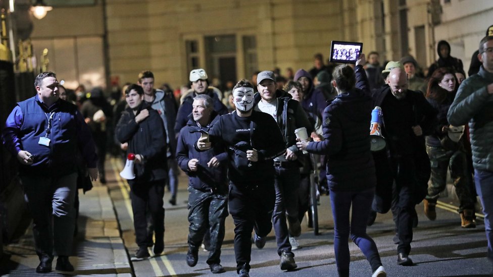 Люди принимают участие в акции протеста против истеблишмента «Марш миллионов масок» на Трафальгарской площади i