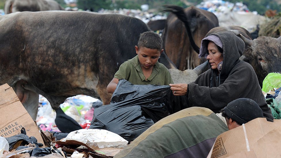 Una mujer y su hijo buscan comida entre la basura.