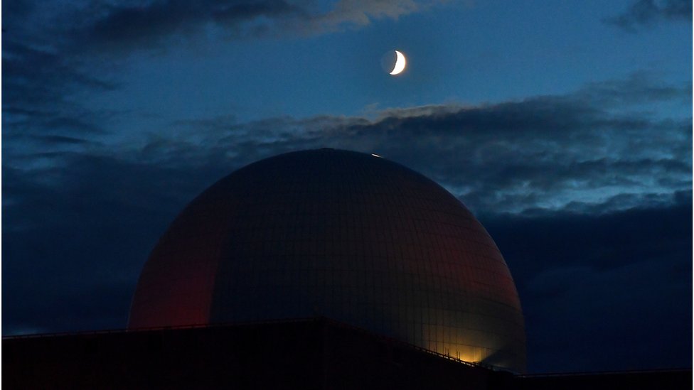 Атомная электростанция с белым куполом под темным небом с полумесяцем