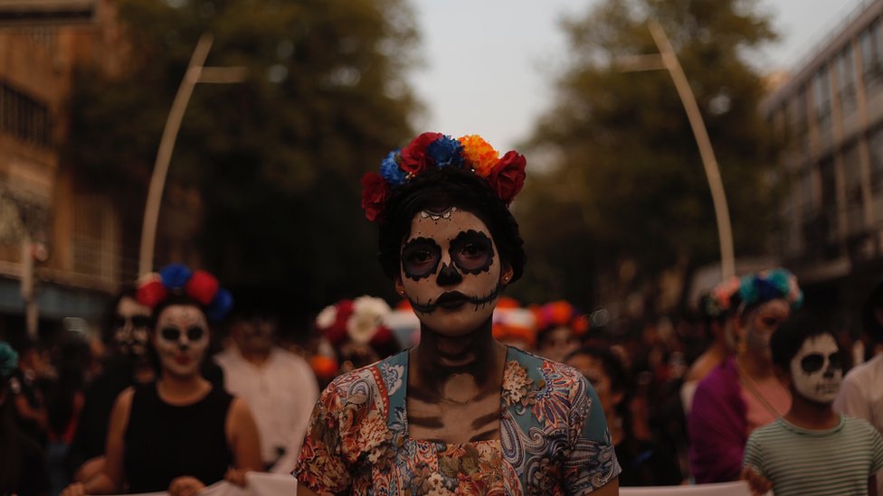 A woman with full skull make-up and flower headband on