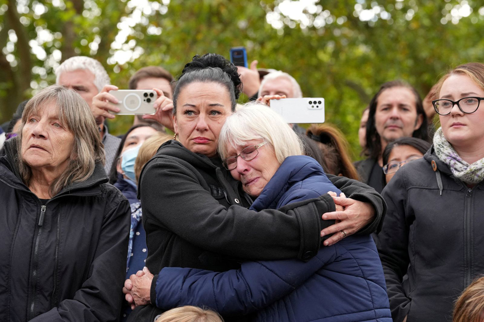 Two women in the crowd comfort each other.