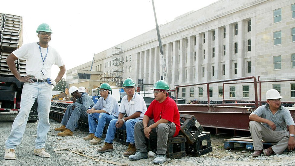 Trabajadores descansan frente a la obra de reconstrucción del Pentágono, junio 2002