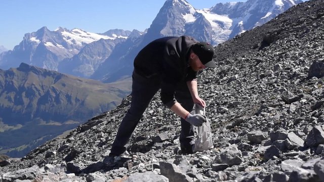 Volunteer collects rubbish in the Swiss Alps