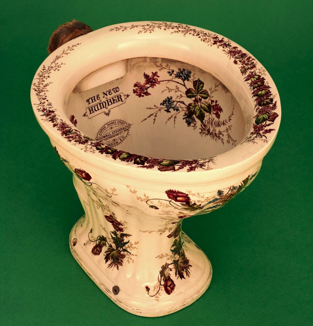 A toilet bowl with flower designs inside and out as well as the words 'The New Humber' printed inside
