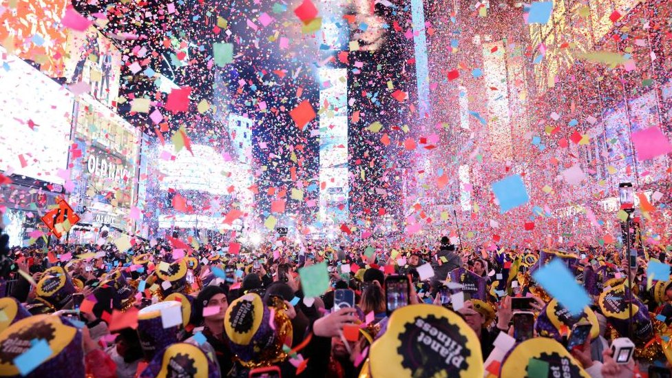 Confetti flies around the countdown clock covering people who've gathered in Times Square in New York to welcome in 2023
