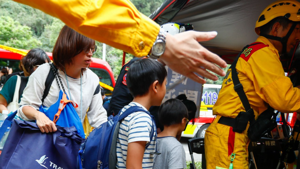 A mum and two children are guided by emergency responders to a medical tent