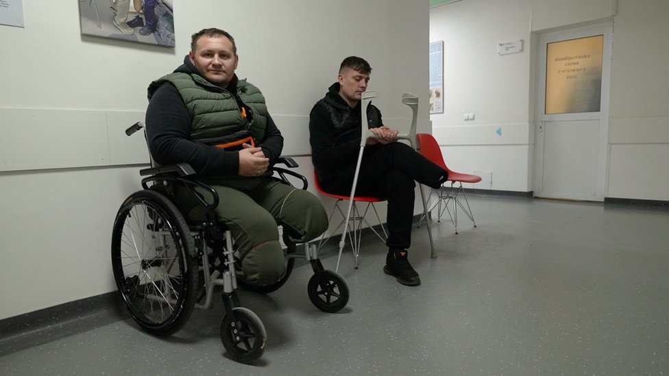 Ukrainian men with injuries sit in the corridor of a rehab centre