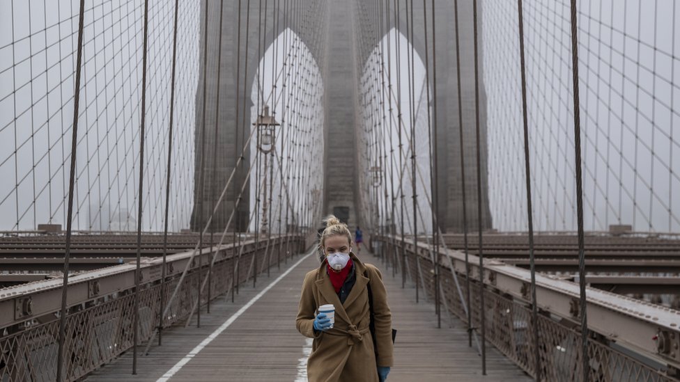 امرأة ترتدي قناعا تمشي على جسر بروكلين في 20 مارس/أذار 2020 في مدينة نيويورك
