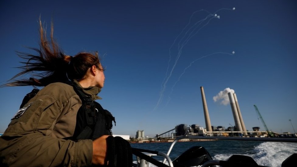 An Israeli soldier looks on as Israel's Iron Dome anti-missile system intercept rockets launched from the Gaza Strip