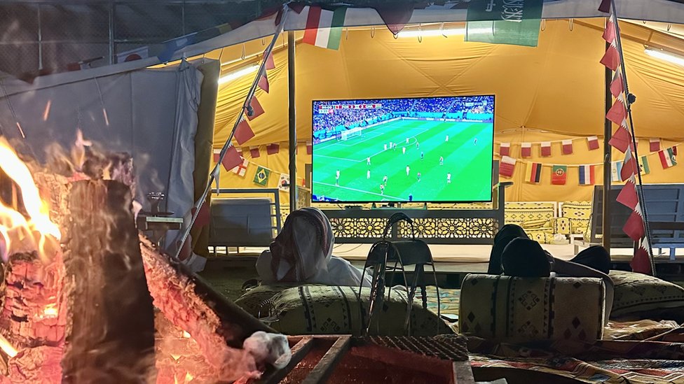 Qataríes viendo el partido delante de la fogata que atempera la noche fresca.