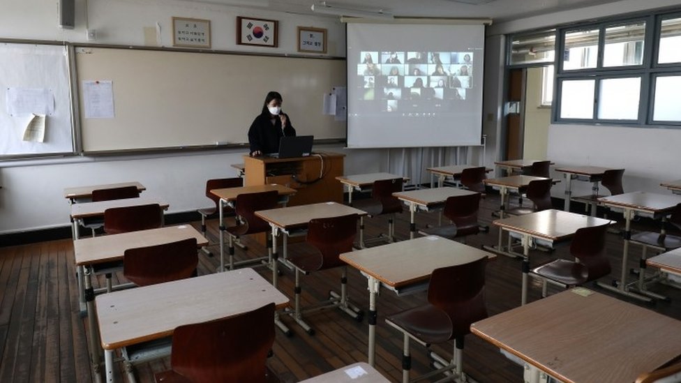Учитель в пустой классной комнате дает онлайн-класс для школьников по видеосвязи