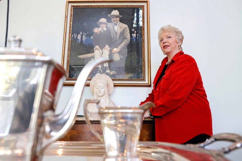 Diane Capone, granddaughter of American gangster Al Capone, stands next to a painting of her grandfather and father, Sonny Capone, from the 1920s before the auction on 5 October 2021