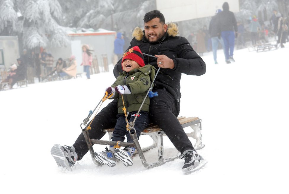 طفل ورجل جزائري يستمتعان بالتزلج على الجليد بالقرب من جبال الأوراس.