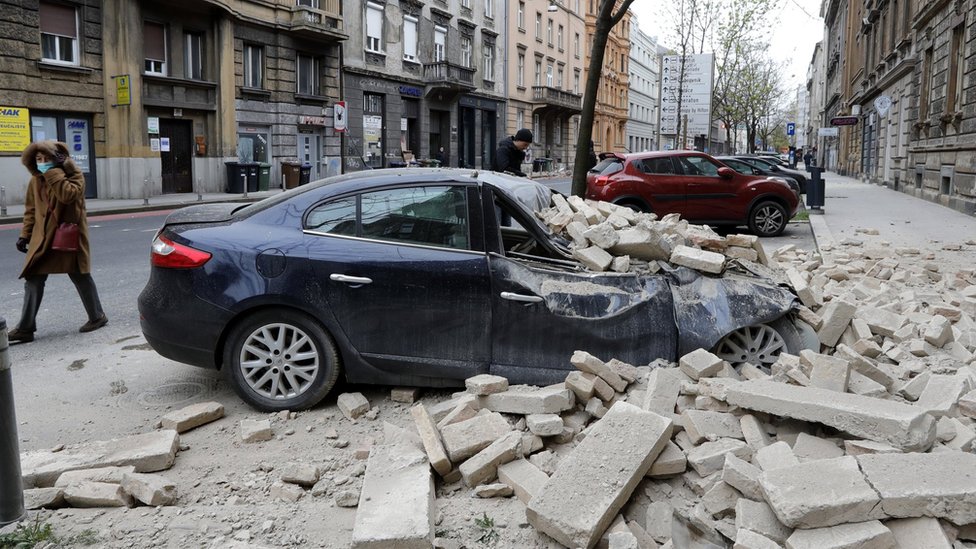 Человек идет мимо завалов, лежащих на улице после землетрясения силой 5,3 балла, произошедшего недалеко от Загреба, Хорватия, 22 марта 2020 года