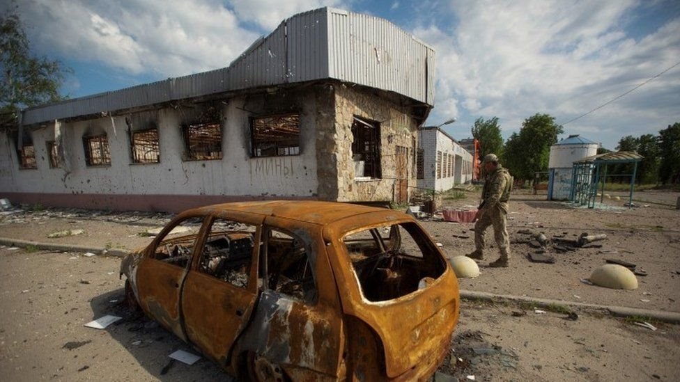 A Ukrainian soldier inspects Russian shell damage in Mariinka, Donetsk region, this weekend