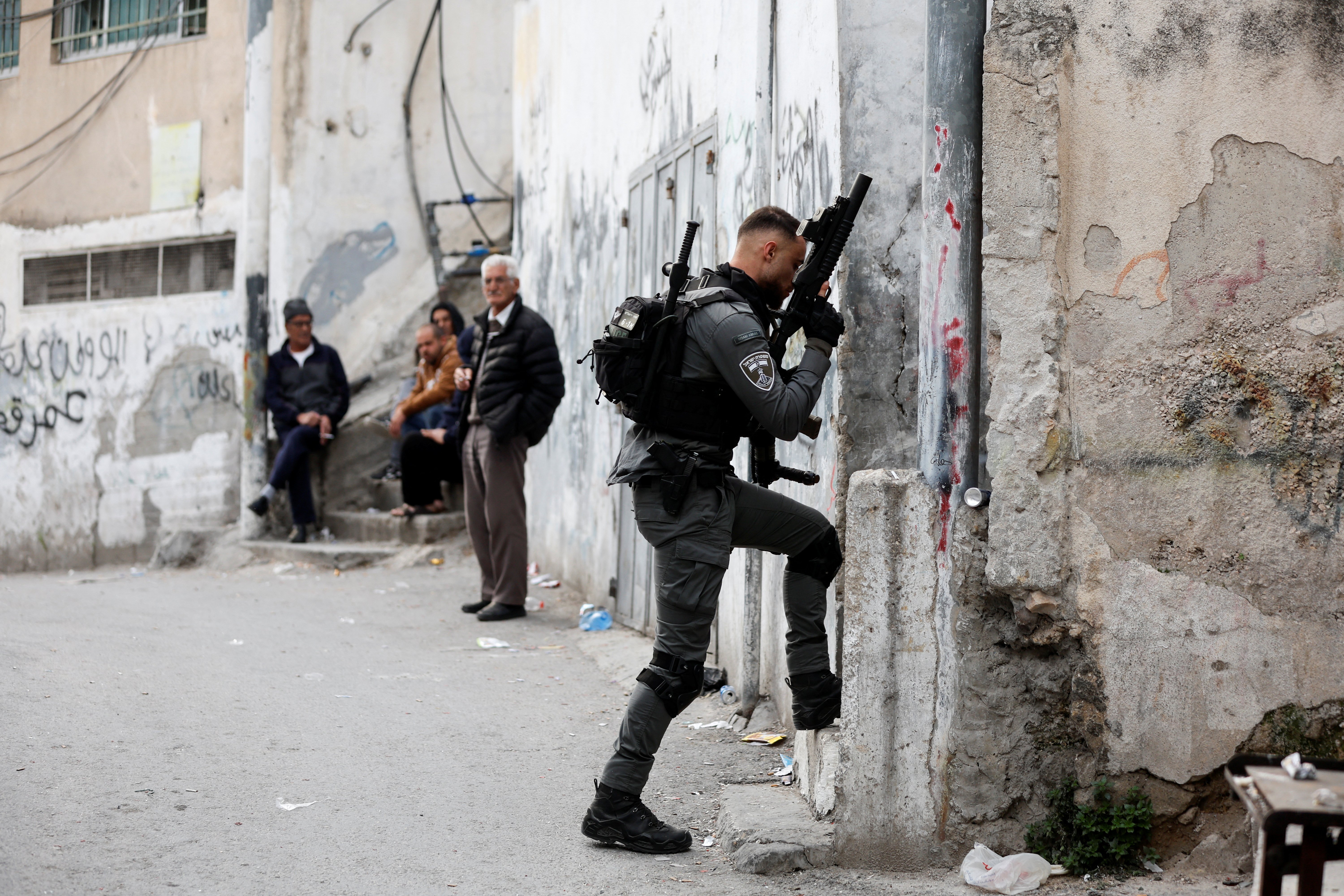 شرطي من شرطة الحدود الإسرائيلية يسير باتجاه منزل منفذ هجوم القدس، الفلسطيني خير علقم في بلدة الطور بالقدس الشرقية، 28 يناير/كانون الثاني 2023.