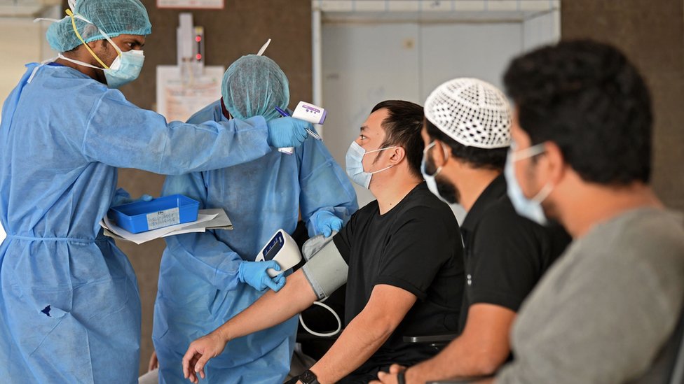Перед тем, как покинуть медицинское учреждение в Дубае, у рабочих-мигрантов медики проверяют температуру и давление (22 апреля 2020 г.)