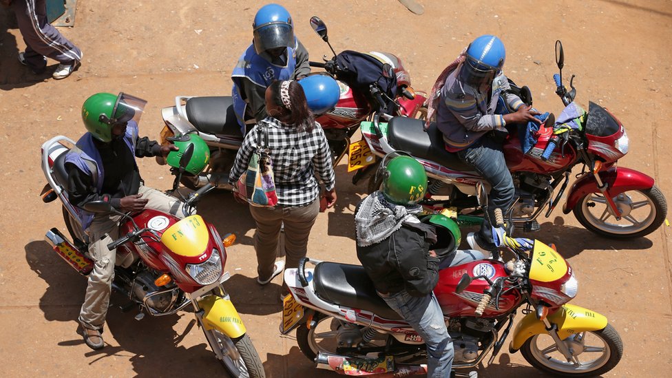 Женщина из Руанды в окружении мотоциклистов