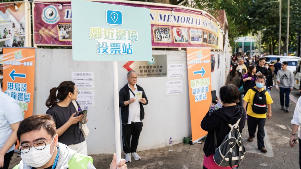 香港新界上水一處「鄰近邊境投票站」外工作人員舉起指示牌引導選民進場（中新社圖片10/12/2023）