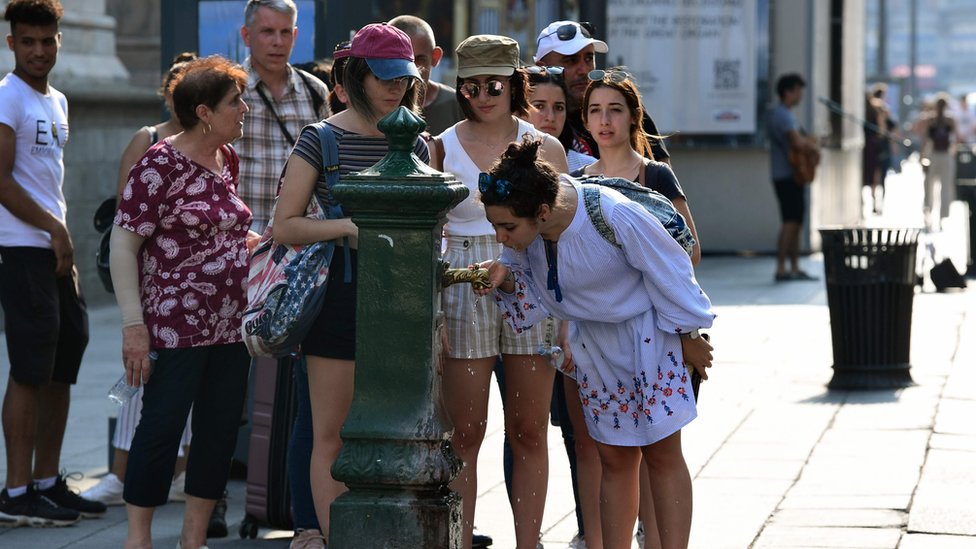 Люди выстраиваются в очередь, чтобы выпить воды из общественного крана возле Кафедрального собора в Милане