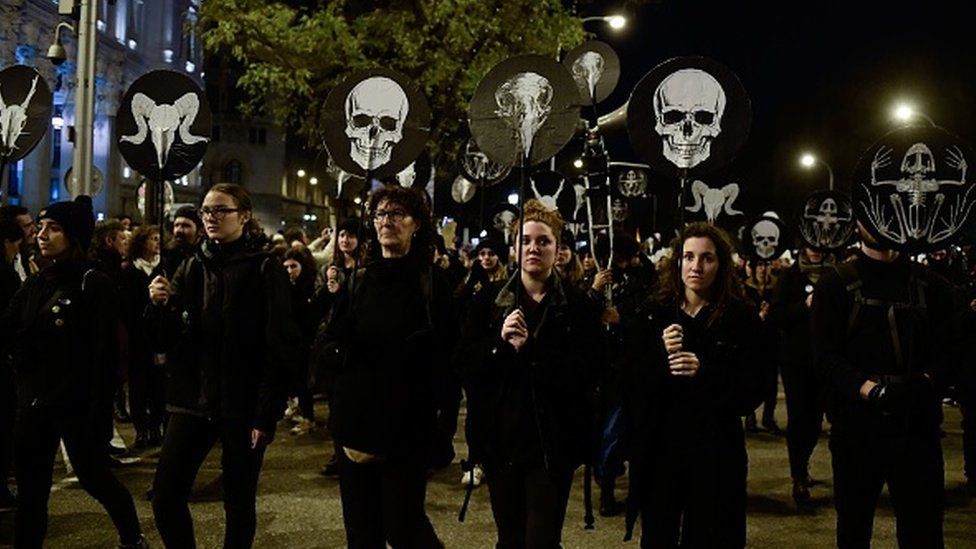 Демонстранты держат маски-черепа во время массового климатического марша