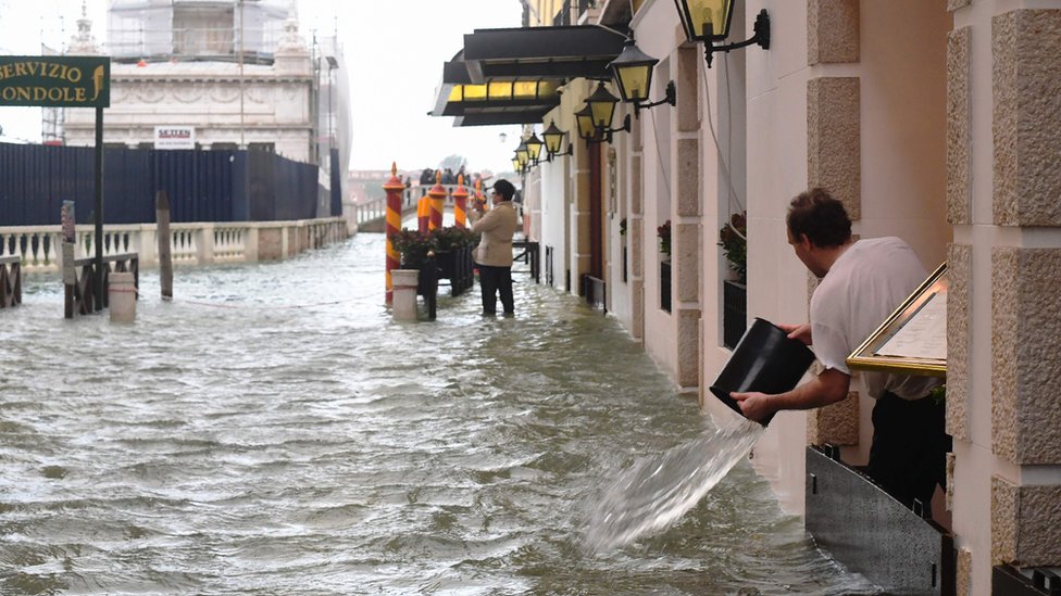 Man empties a bucket of water in Venice on 29 October 2018