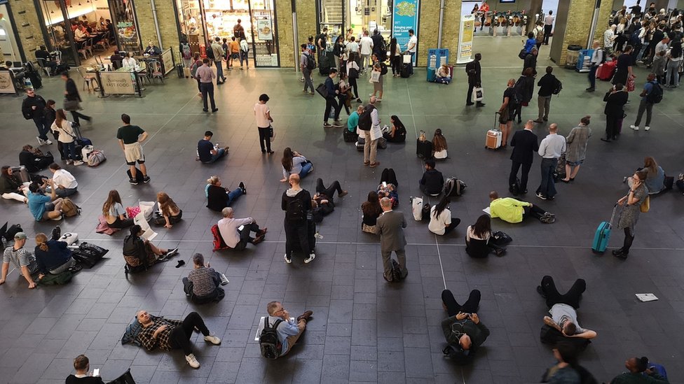Люди ждут на вокзале Кингс-Кросс в Лондоне, так как все услуги на станции и из нее были приостановлены из-за большого отключения электроэнергии