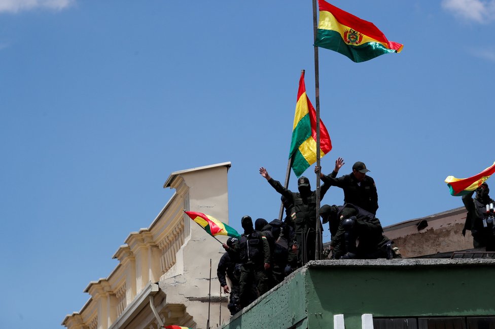 Полицейские развевают флаги на крыше полицейского участка в Ла-Пасе в субботу