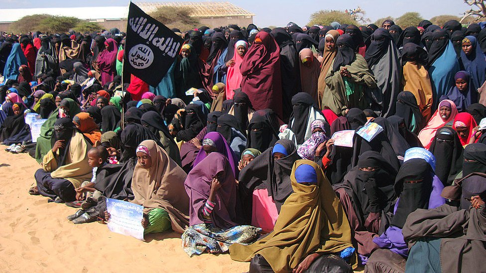 Un grupo de mujeres mirando a los combatientes de Al-Shabab tras una demostración.