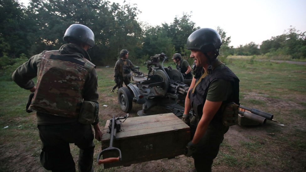 Ukrainian artillerymen carrying a crate