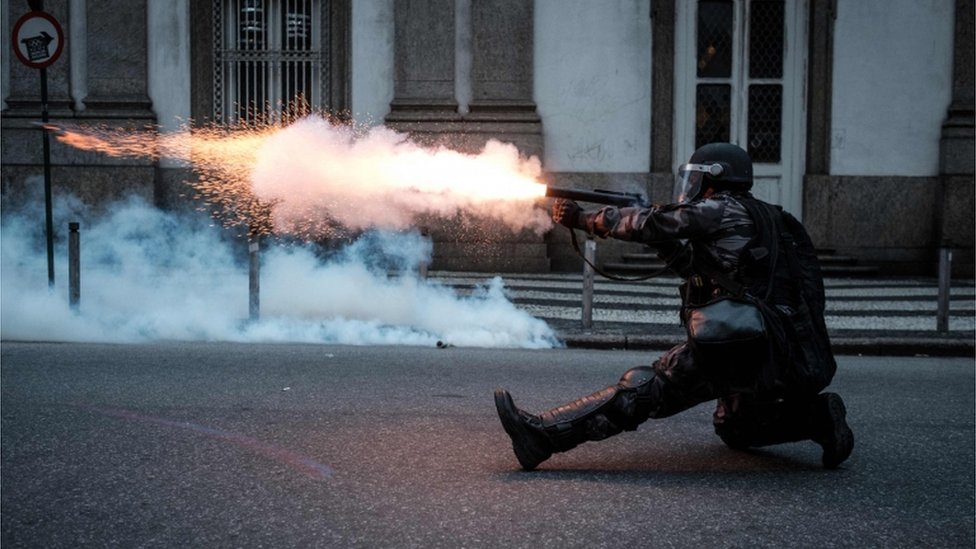 Военный полицейский стреляет по демонстрантам в Рио-де-Жанейро.