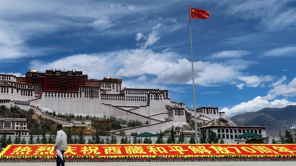 Dvorec Potala. Okolo nego ustanovlen kitaйskiй flag i znak v čestь 70-letiя ustanovleniя Kitaem kontrolя nad Tibetom.