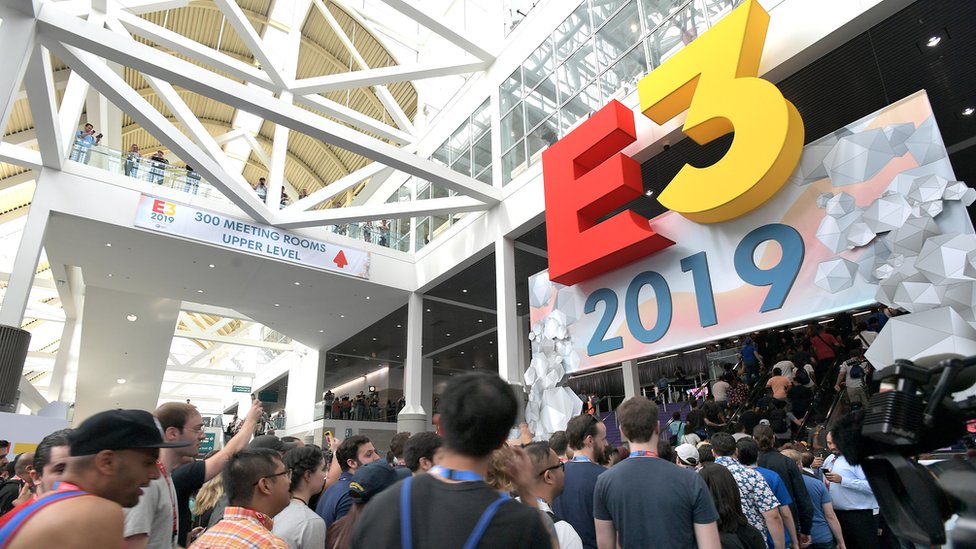 Логотип E3 находится над дверью, когда сотни посетителей проходят через вход в конференц-центр