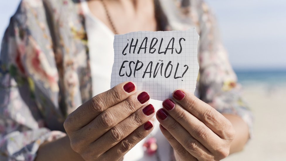 Una mujer sostiene un cartel que dice ¿hablas español?