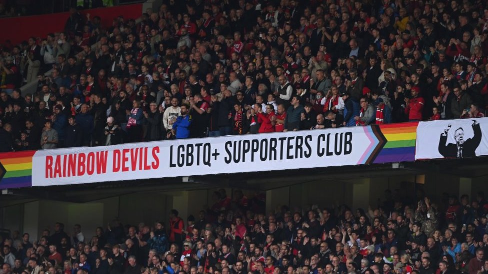 Uma faixa de um grupo de torcedores LGBTQ+ do Manchester United