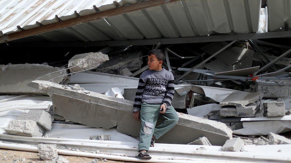 طفل فلسطيني بجوار منزل مدمر في غزة