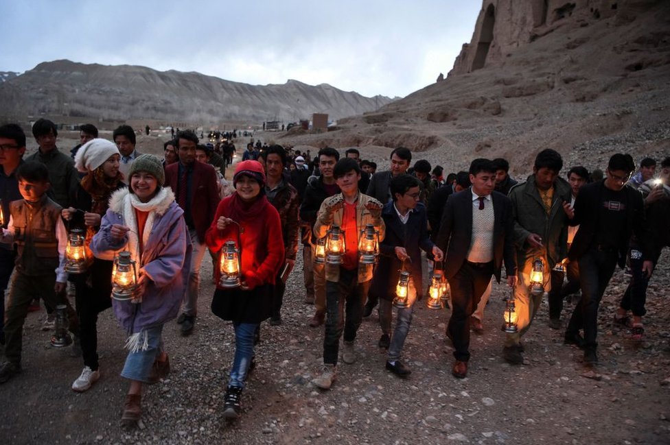 Residents and civil society activists hold lamps as they walk to the site where the Salsal Buddha statue once stood