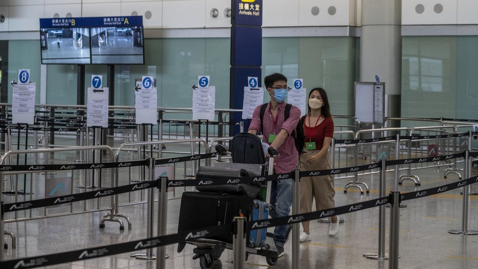 香港國際機場客運大樓抵達大堂內一對男女推著行李手推車前行（1/8/2022）