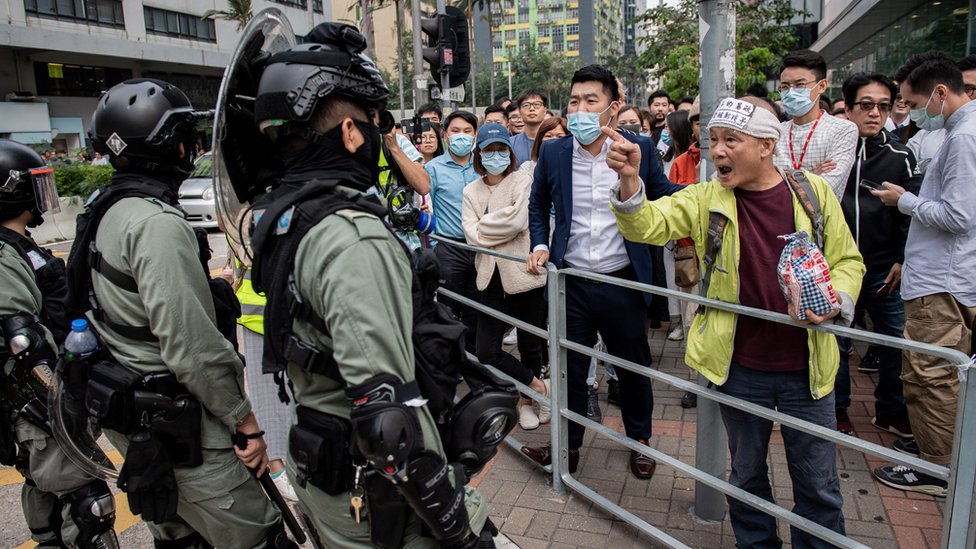 ОМОН (слева) прибыл, чтобы разогнать людей, собравшихся в поддержку протестующих за демократию во время митинга в районе залива Коулун в Гонконге 26 ноября 2019 г.