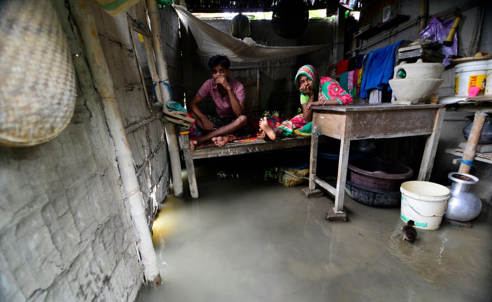 Пара сидит на кровати, поскольку их дом затопил паводковые воды в пострадавшем от наводнения районе Моригаон в Ассаме, Индия, 12 июля 2019 г.
