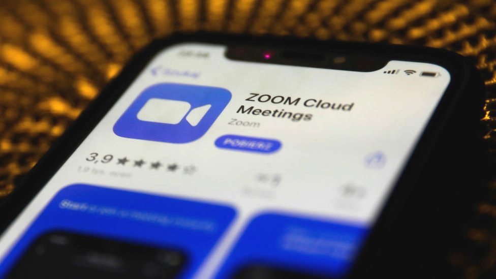 Экран установки приложения Zoom отображается на дисплее смартфона, когда сам телефон лежит напротив