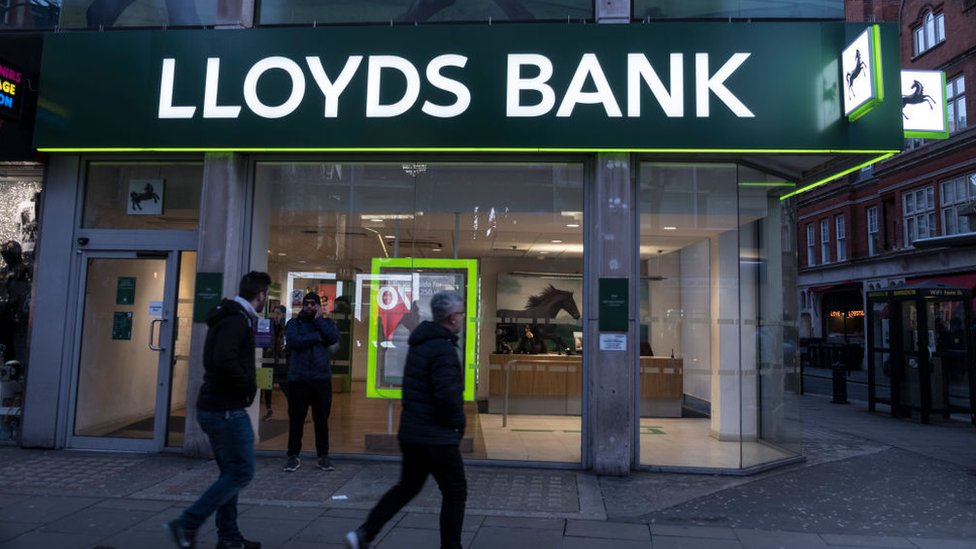 Люди проходят мимо отделения банка Lloyds