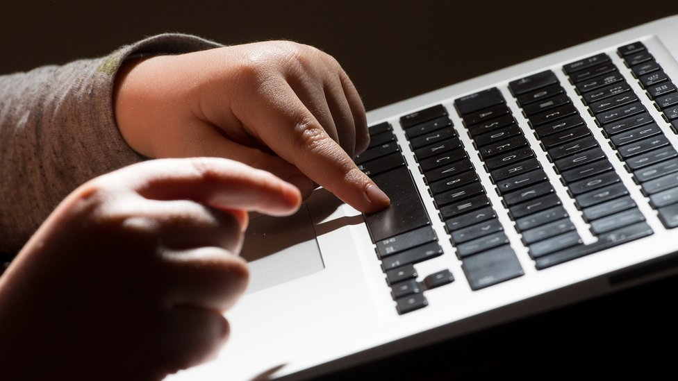 ребенок печатает на клавиатуре компьютера