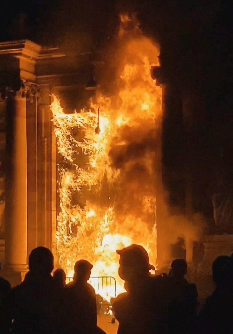 People look at the Bordeaux town hall in flames during a demonstration as part of the ninth day of nationwide strikes and protests against the French government's pension reform, in Bordeaux, France, March 23, 2023, in this screengrab obtained from a social media video.
