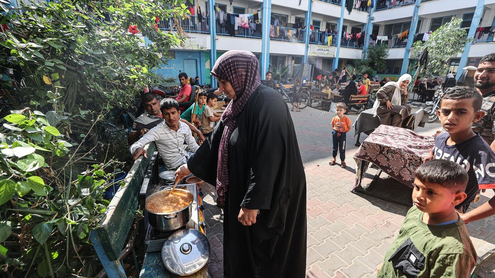 加沙汗尤尼斯一所聯合國近東救濟工程處學校內一位避難的老太太在庭院的長椅上生火做飯（14/10/2023）